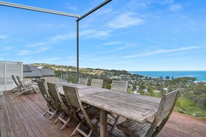 A wooden deck with a table and chairs overlooking a coastal town.