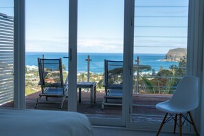 Un balcón con dos sillas y una mesa, con vistas a la costa.