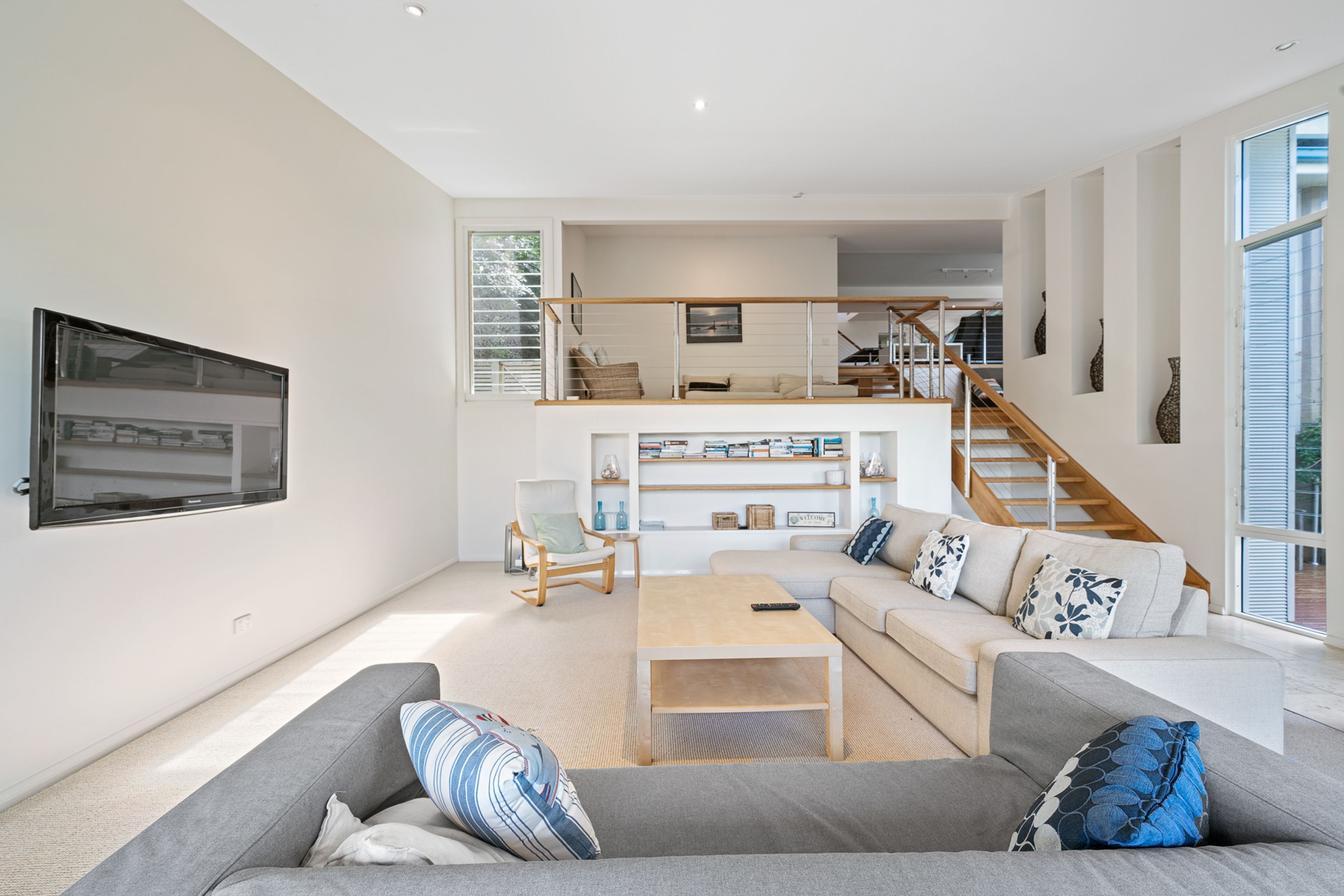 A spacious living area with a sofa, coffee table, and a staircase leading to an upper level.