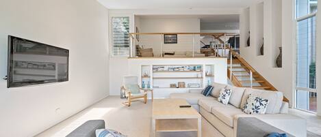 A spacious living area with a sofa, coffee table, and a staircase leading to an upper level.
