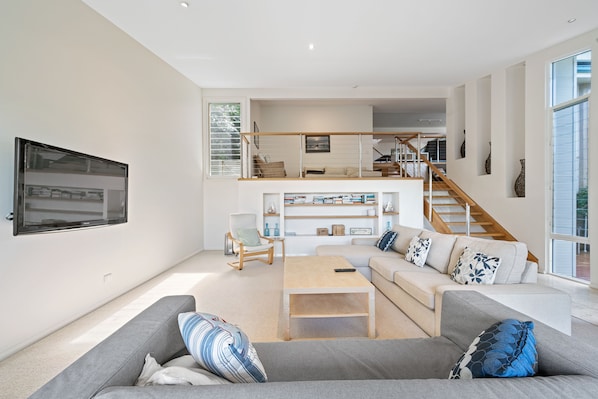 A spacious living area with a sofa, coffee table, and a staircase leading to an upper level.