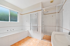 A bathroom with a bathtub, a shower, and a window.