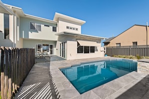 A residential property with a swimming pool, a patio area, and a fenced backyard.