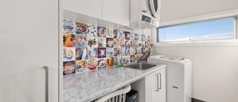 Cozinha compacta com painel de azulejos, máquina de lavar embutida e janela que proporciona iluminação natural.