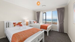 Habitación de hotel con dos camas, un ventanal con vista al mar y una lámpara de techo.