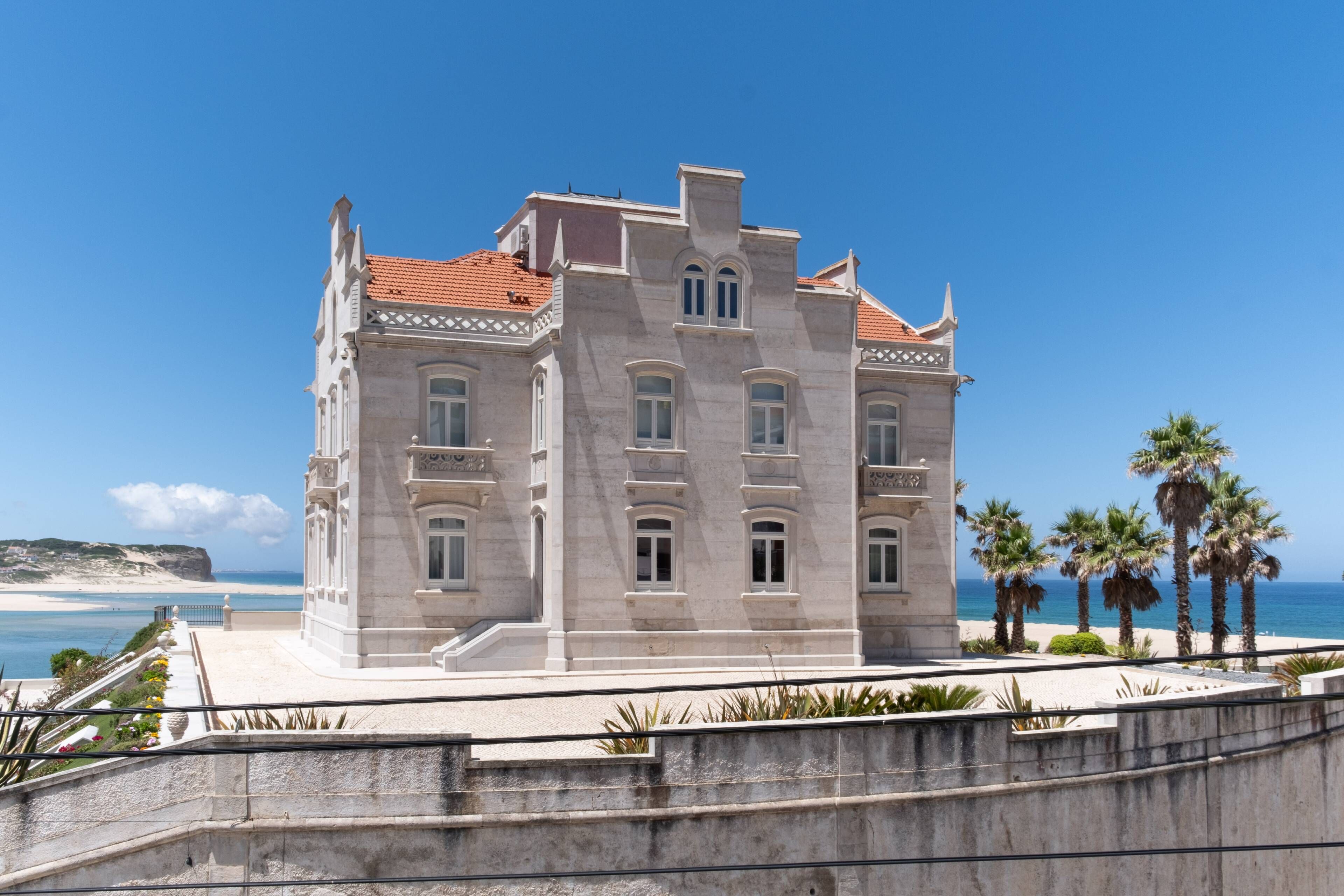 A large, multi-story building with a classical architectural style, featuring a symmetrical facade, arched windows, and a red-tiled roof.