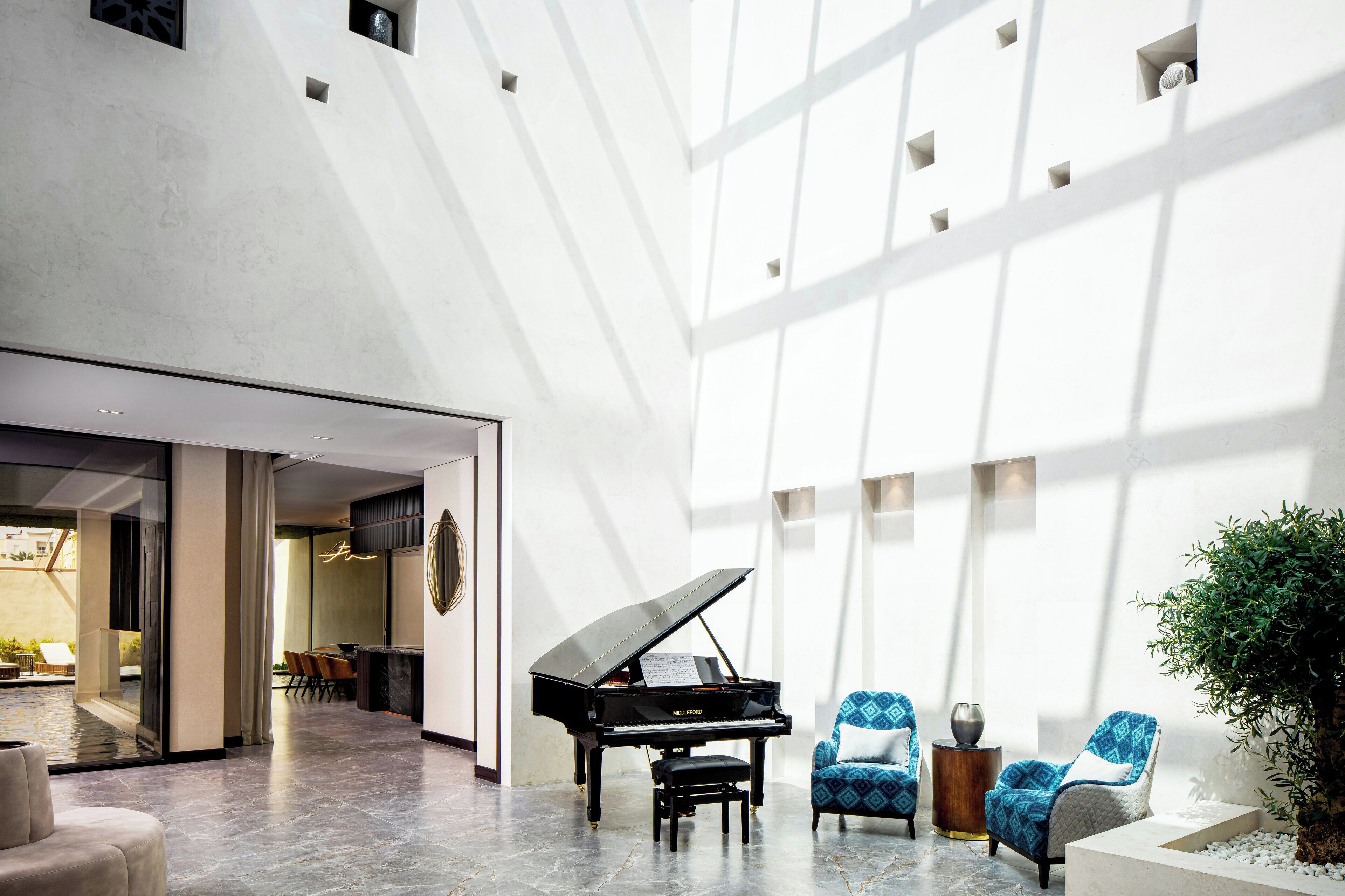 A spacious lobby with a grand piano, modern seating, and a large window allowing natural light.