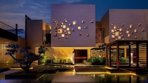 A modern building with a geometric facade, recessed lighting, and a reflective pool area.