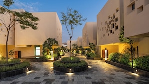 A courtyard with a central circular garden, surrounded by buildings with uniform architecture and small windows.