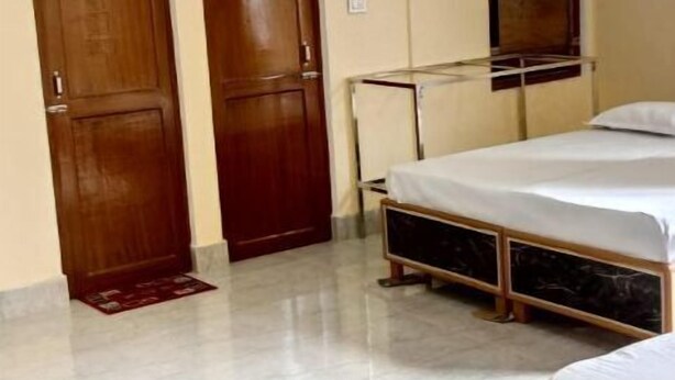 Quarto de hotel com cama, ventoinha no teto e duas portas de madeira.