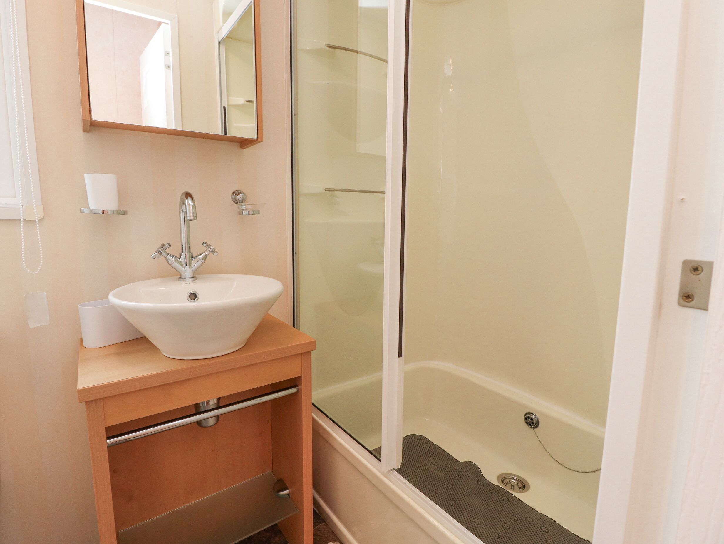 A bathroom with a sink, mirror, and shower.