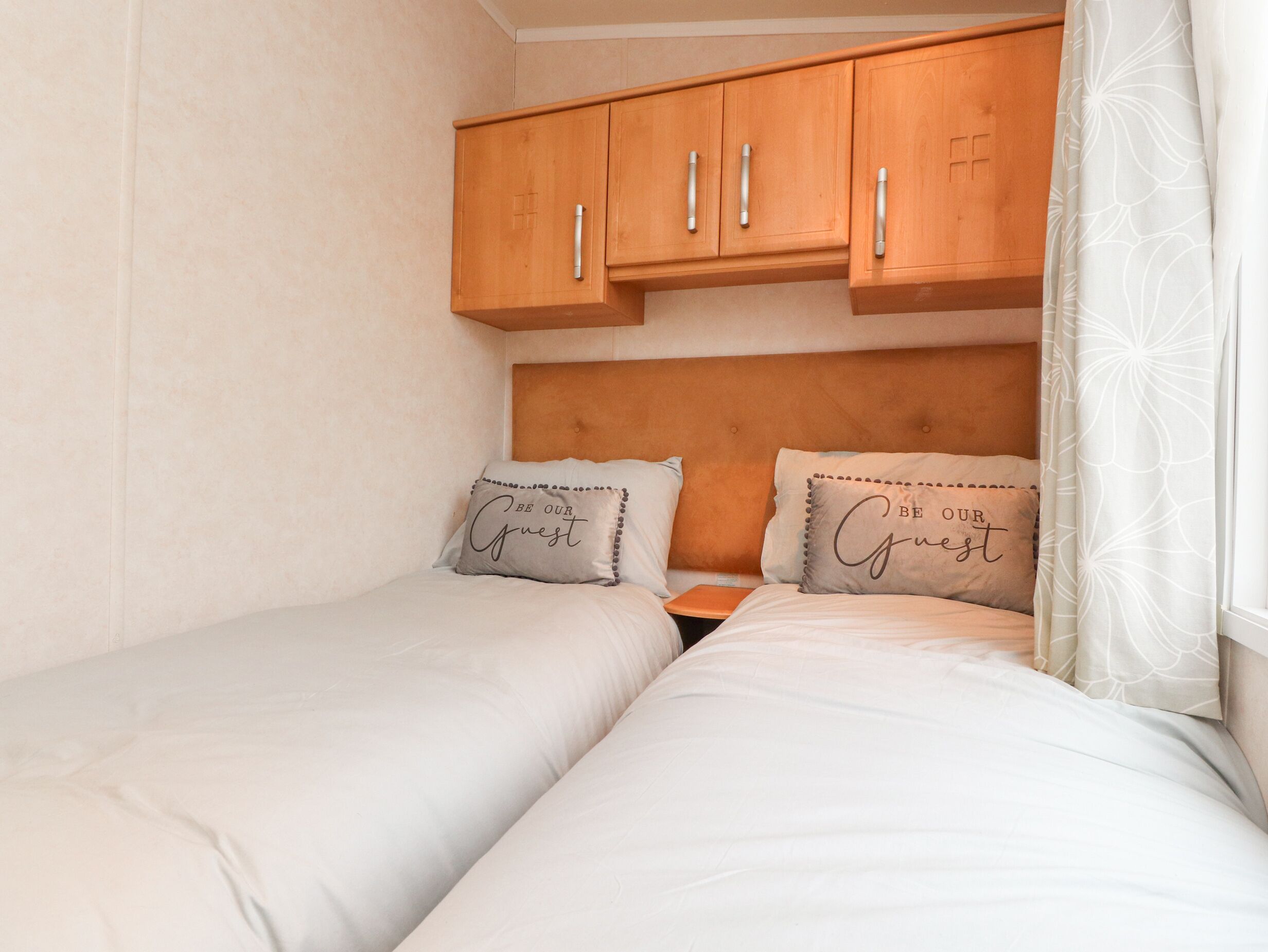A double bed with two pillows, a wooden headboard, and a wooden wardrobe above.