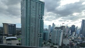 Un edificio de gran altura con fachada de vidrio, un río en primer plano y un paisaje urbano al fondo.