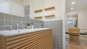 A modern bathroom with a large mirror, two sinks, wooden vanity, and a chair. - Walk Downtown, Free Parking, By Conch House, Games (St. Augustine)