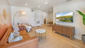 A modern living room with a sofa, a round coffee table, a TV mounted on the wall, and a cabinet. - Walk Downtown, Free Parking, By Conch House, Games (St. Augustine)