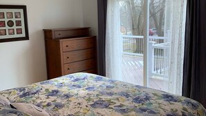 Un dormitorio con cama, ventilador de techo, cómoda y puerta corrediza de vidrio que da a un balcón.