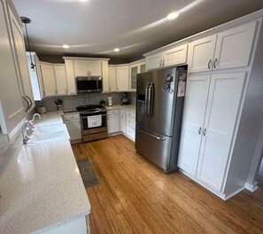 Una cocina moderna con armarios blancos, electrodomésticos de acero inoxidable y piso de madera.