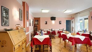 A dining area with tables set for meals, a wooden cabinet, and framed pictures on the walls. - Albergo Mancuso del Voison (Aosta)