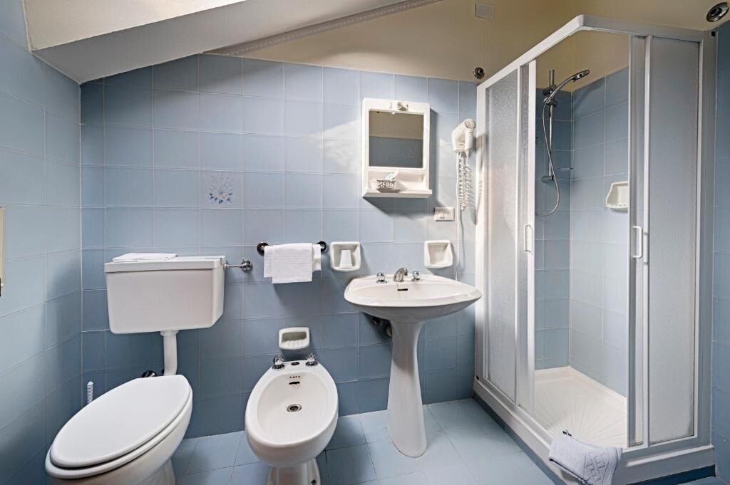 Une salle de bain comprenant des toilettes, un bidet, un lavabo et une douche à l’italienne.