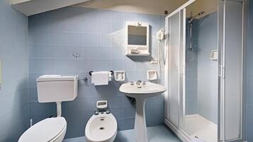 Une salle de bain comprenant des toilettes, un bidet, un lavabo et une douche à l’italienne.