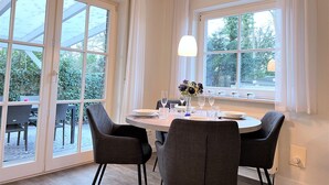 Ein Essbereich mit einem runden Tisch, vier Stühlen und einer Blumenvase.