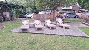 Eine Holzterrasse mit Liegestühlen und einer überdachten Veranda.