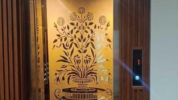 An elevator with a decorative panel featuring a floral design. - Hotel Madhavam (Mathura)