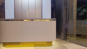 A modern reception desk with a metallic base and a vertical panel. - Hotel Madhavam (Mathura)