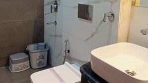 A modern bathroom with a built-in shower, a toilet, and a sink. - Hotel Madhavam (Mathura)
