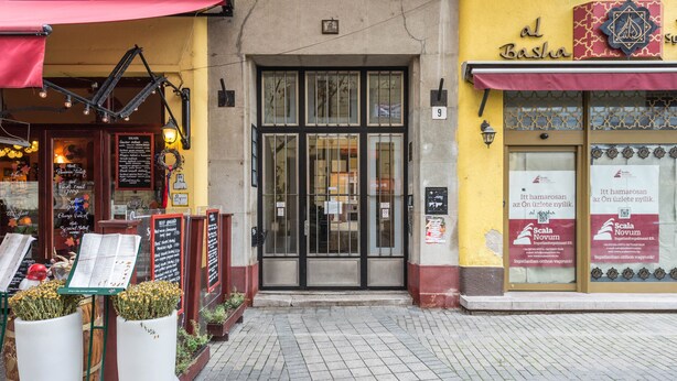 A storefront with a yellow facade, a sign reading "al Basha", and a large glass door entrance.