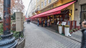 A street with a cafe named 'Cafe Qian' featuring a red awning and outdoor seating.