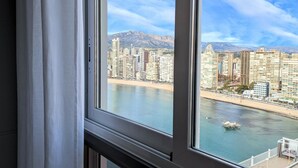 Un paysage urbain avec de hauts immeubles, une plage et des montagnes en arrière-plan.