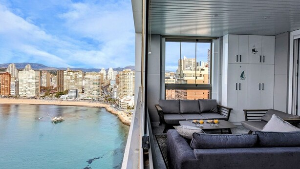 Un salon moderne avec vue sur la ville, un balcon et un coin repas comprenant une table et des chaises.