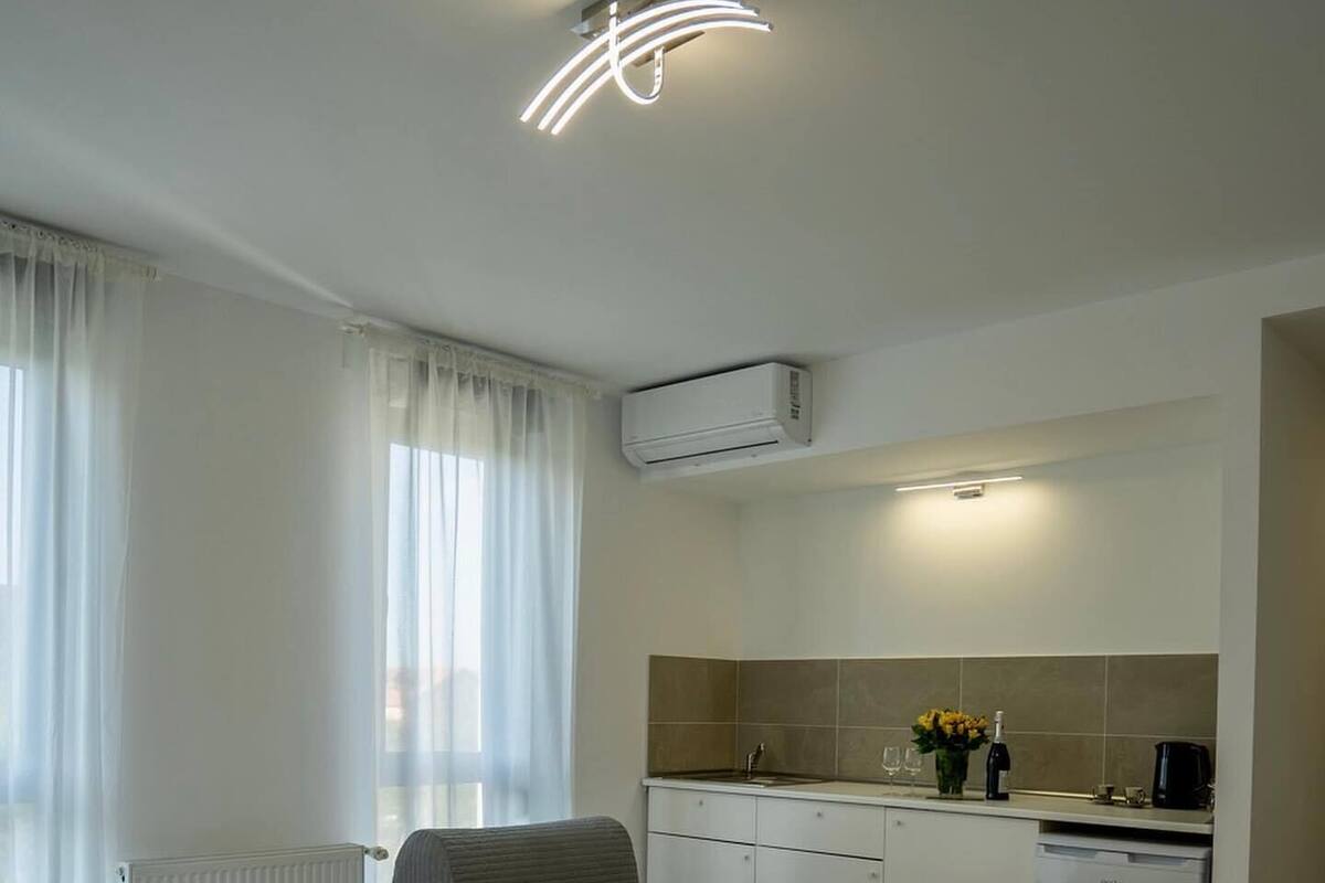 Ein Hotelzimmer mit zwei Betten, einer Küchenzeile, einer Klimaanlage und einem Fenster mit Vorhängen.
