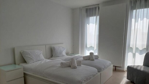 Una camera da letto moderna con un letto grande, due comodini e una poltrona.