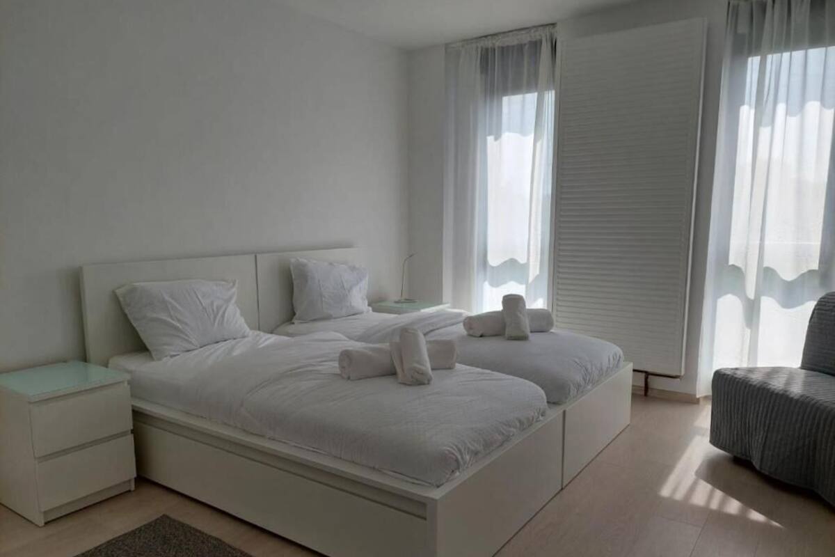 Ein modernes Schlafzimmer mit einem großen Bett, zwei Nachttischen und einem Sessel.