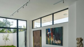 Un soggiorno moderno con un divano nero, ampie finestre e quadri astratti.
