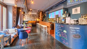 Un espace bar comprenant un comptoir de réception, des sièges et un tableau noir où sont affichés des messages.