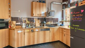 A modern kitchen with wooden cabinets, a built-in oven, and a refrigerator with a note asking guests to label their food.