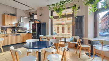 Ein modernes Café mit Holztischen und -stühlen, einer Küchenzeile und großen Fenstern mit Blick auf die Straße.