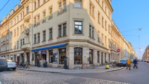 Un edifici amb cantonada i diverses finestres, una tenda blava i un rètol de restaurant.