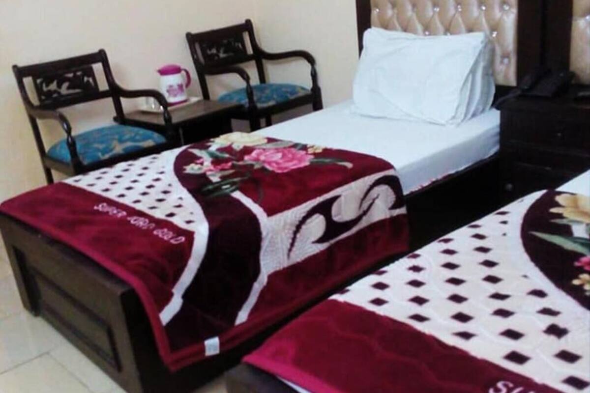 Ein Hotelzimmer mit einem Bett, zwei Stühlen, einem kleinen Tisch und einem Nachttisch.