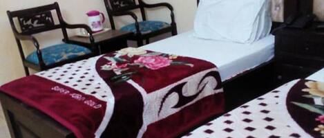A hotel room with a bed, two chairs, a small table, and a nightstand.
