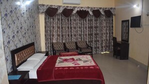 A bedroom with a bed, a nightstand, a dresser, a mirror, and a TV.