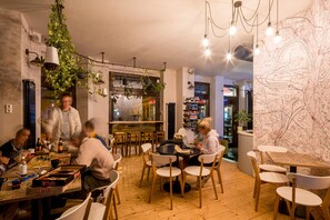 Ein gemütliches Restaurant mit Holztischen und -stühlen, hängenden Pflanzen und einer Karte an der Wand.