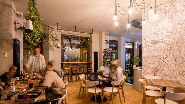 A cozy restaurant with wooden tables and chairs, hanging plants, and a map on the wall. - Doppelzimmer mit Bad (Dresden)