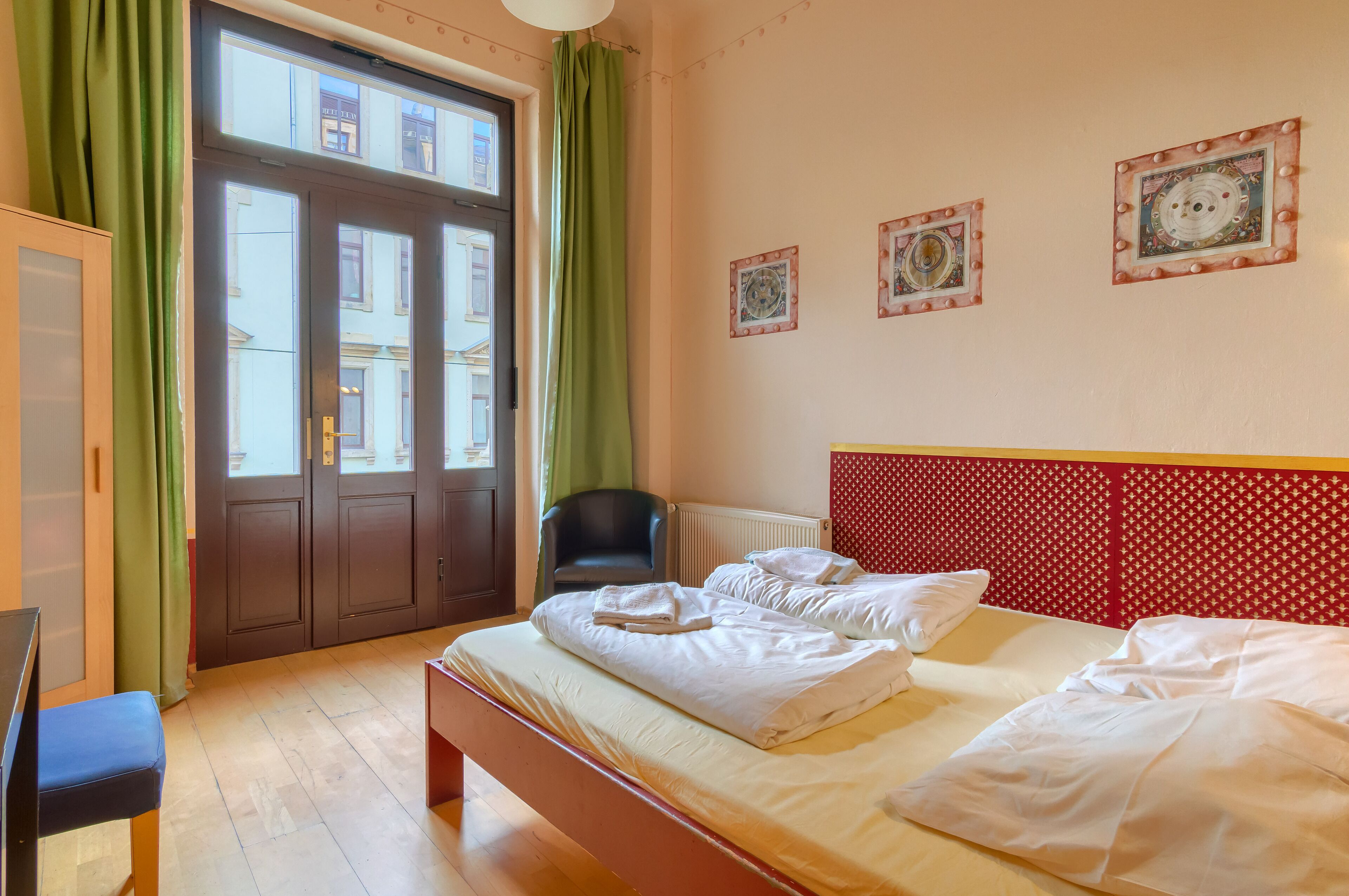 Ein Hotelzimmer mit großem Fenster, einem Bett mit weißer Bettwäsche, einem Sessel und einer Heizung.