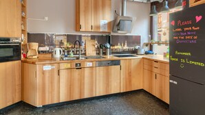 A compact kitchen with wooden cabinets, a built-in oven, and a refrigerator with a note. - Doppelzimmer mit Bad (Dresden)