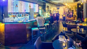 A bar area with stools and tables, a bar counter with bottles, and a menu on the wall. - Doppelzimmer mit Bad (Dresden)