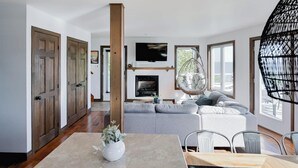 Ein modernes Wohnzimmer mit Kamin, einer Hängeschaukel und einem Essbereich mit Tisch und Stühlen.